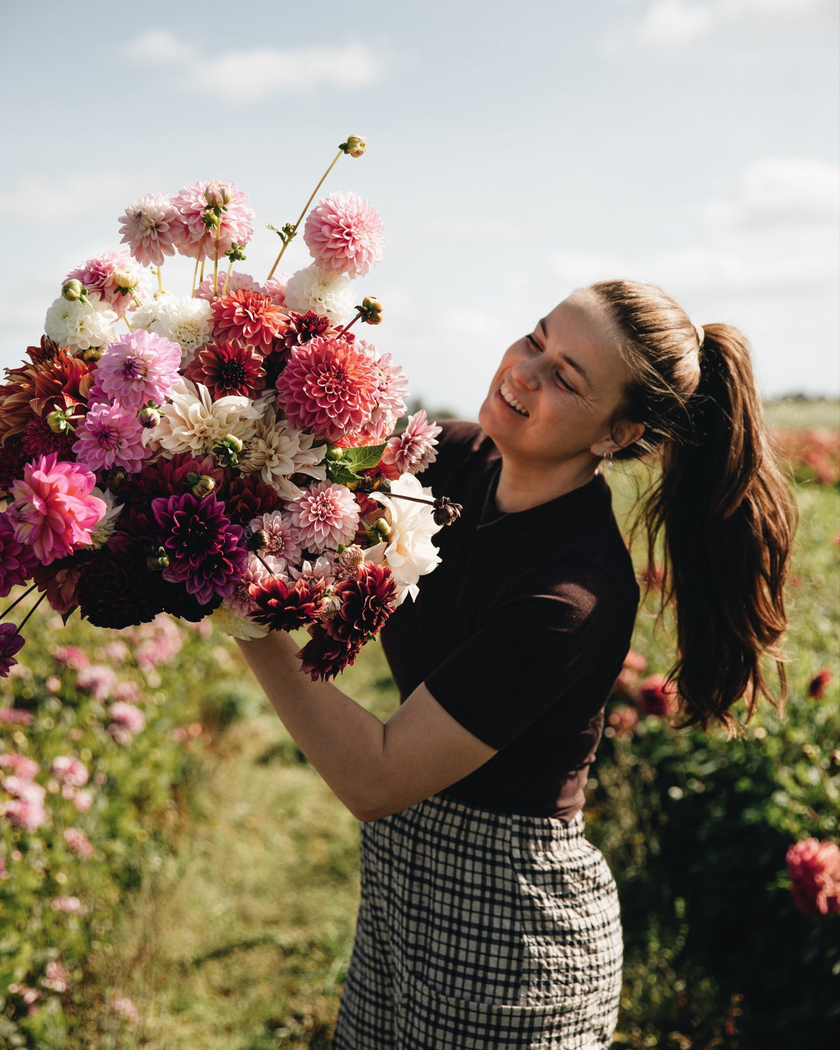 Merel met een arm vol biologische dahlia's op het dahliaveld van De Groene Makers
