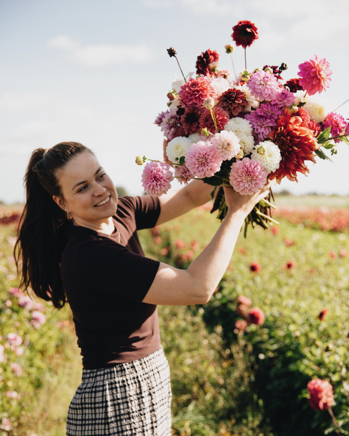 Merel houdt een groot boeket biologische dahlia's omhoog